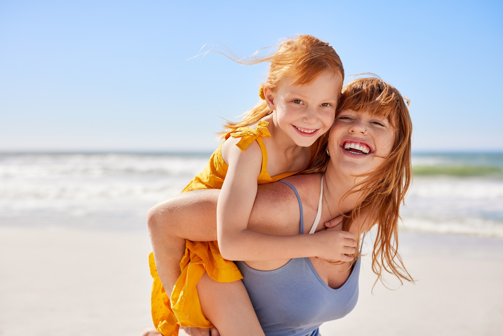 Mother and daughter smiling on a sunny beach